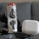 The Nothing Ear (stick) wireless earbuds in their cylindrical charging case next to the third-gen Apple AirPods in their charging case.